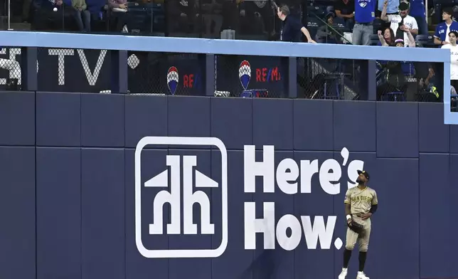 San Diego Padres left fielder Jason Heyward (22) watches Toronto Blue Jays' Vladimir Guerrero Jr.'s solo home run clear the fence during the first inning of a baseball game in Toronto on Tuesday, May 20, 2025. (Jon Blacker/The Canadian Press via AP)