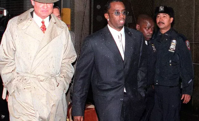 FILE - Rap artist and music producer Sean "Puffy" Combs, center, leaves a court hearing at New York's Manhattan Criminal Court on April 16, 1999, after Combs was charged with beating rap record executive, Steven Stoute, the previous day. (AP Photo/Robert Mecea, File)