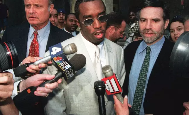FILE - Rapper Sean "Puffy" Combs, center, speaks to the media outside of court in New York after his assault case was postponed on June 24, 1999. (AP Photo/Lynsey Addario, File)