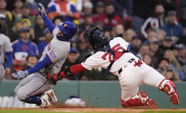 New York Mets' Luis Torrens, left, is tagged out by Boston Red Sox catcher Carlos Narváez while trying to score on a single by Brett Baty during the first inning of a baseball game at Fenway Park, Wednesday, May 21, 2025, in Boston. (AP Photo/Charles Krupa)
