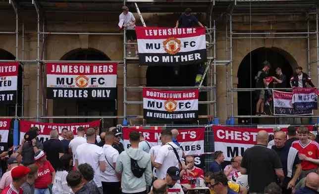 Manchester United supporters place banners on scaffolding ahead of the Europa League final soccer match between Tottenham Hotspur and Manchester United at the San Mamés Stadium in Bilbao, Spain, Wednesday, May 21, 2025. (AP Photo/Manu Fernandez)