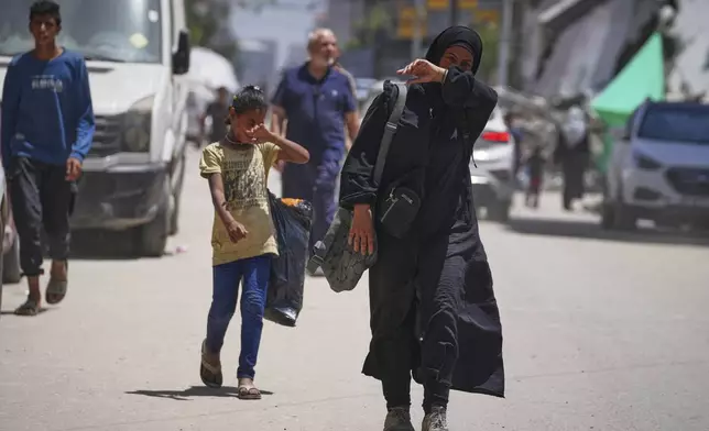 Islam Abu Taeima, a 40-year-old mother of five, right, and her 9-year-old daughter Waed walk back to their tent after searching for food in a pile of garbage in Gaza City, Sunday, May 25, 2025. (AP Photo/Jehad Alshrafi)