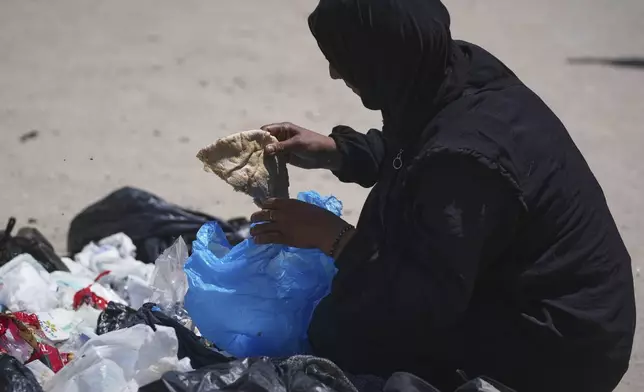 In a sign of growing desperation, Islam Abu Taeima, a 40-year-old mother of five, grabs a piece of bread from a pile of garbage in Gaza City, Sunday, May 25, 2025.(AP Photo/(AP Photo/Jehad Alshrafi)