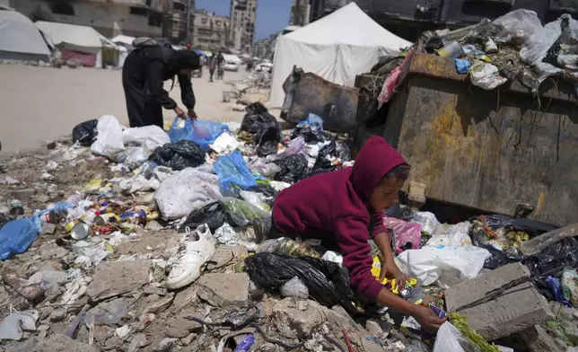 Islam Abu Taeima, a 40-year-old mother of five, left, and a boy look for some food on a pile of garbage in Gaza City, Sunday, May 25, 2025.(AP Photo/Jehad Alshrafi)