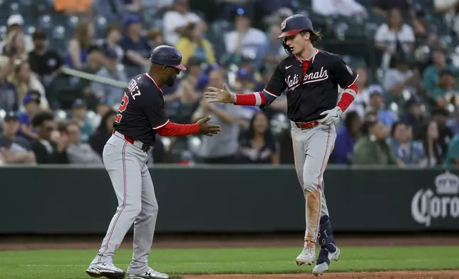 Washington Nationals' Robert Hassell III, right, celebrates his first career home run with third base coach Ricky Gutierrez during the eighth inning of a baseball game against the Seattle Mariners Wednesday, May 28, 2025, in Seattle. (AP Photo/Ryan Sun)
