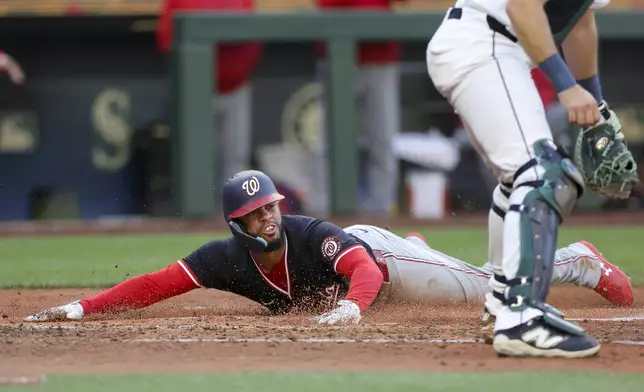 Washington Nationals' Luis Garcia Jr. slides home to score past Seattle Mariners catcher Cal Raleigh off a single hit by Robert Hassell III during the fourth inning of a baseball game Wednesday, May 28, 2025, in Seattle. (AP Photo/Ryan Sun)