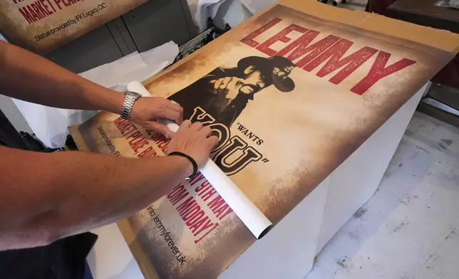 A man is preparing posters as Motorhead fans meet to commemorate Lemmy Kilmister the Motorhead frontman in Burslem, Stoke on Trent, England, Friday, May 9, 2025. The musician, once described as having 'one of the most recognizable voices in rock', was born in Burslem and a statue has been crafted by acclaimed local sculptor and lifelong Motorhead fan Andy Edwards. (AP Photo/Kirsty Wigglesworth)