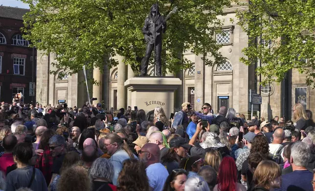 Motorhead fans gather around a statue to commemorate Lemmy Kilmister the Motorhead frontman in Burslem, Stoke on Trent, England, Friday, May 9, 2025. The musician, once described as having 'one of the most recognizable voices in rock', was born in Burslem and a statue has been crafted by acclaimed local sculptor and lifelong Motorhead fan Andy Edwards. (AP Photo/Kirsty Wigglesworth)