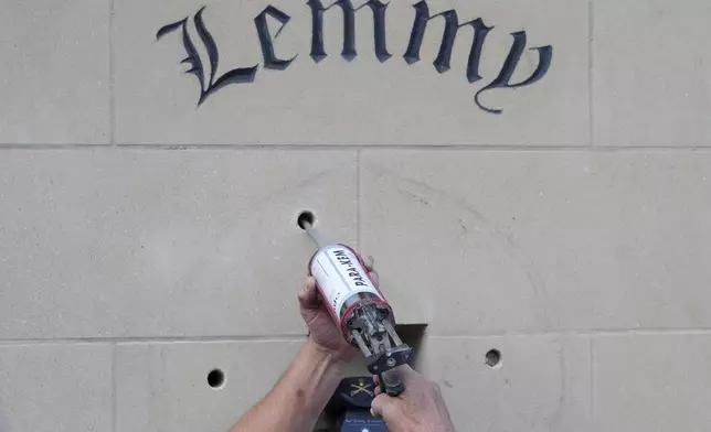 A man fills wholes of a statue of Lemmy Kilmister the former Motorhead frontman in Burslem, Stoke on Trent, England, Friday, May 9, 2025. The musician, once described as having 'one of the most recognizable voices in rock', was born in Burslem and a statue has been crafted by acclaimed local sculptor and lifelong Motorhead fan Andy Edwards. (AP Photo/Kirsty Wigglesworth)