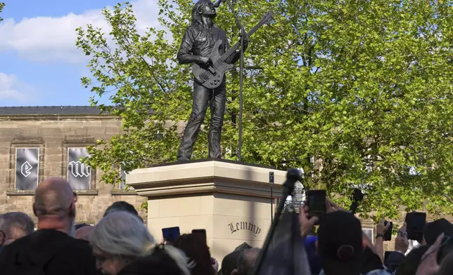 Motorhead fans take pictures of a statue to commemorate Lemmy Kilmister the Motorhead frontman in Burslem, Stoke on Trent, England, Friday, May 9, 2025. The musician, once described as having 'one of the most recognizable voices in rock', was born in Burslem and a statue has been crafted by acclaimed local sculptor and lifelong Motorhead fan Andy Edwards. (AP Photo/Kirsty Wigglesworth)
