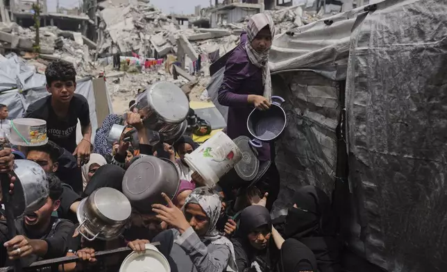 Palestinians struggle to get donated food at a community kitchen in Jabalia, northern Gaza Strip, Thursday, May 15, 2025. (AP Photo/Jehad Alshrafi)
