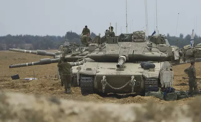 Israeli soldiers work on tanks and APCs at a staging area near the border with the Gaza Strip, in southern Israel, Thursday, May 15, 2025. (AP Photo/Ariel Schalit)