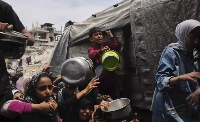 Palestinians struggle to get donated food at a community kitchen in Jabalia, northern Gaza Strip, Thursday, May 15, 2025. (AP Photo/Jehad Alshrafi)