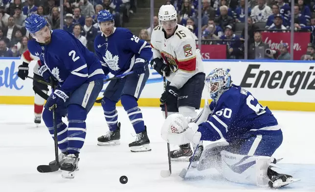 Toronto Maple Leafs goaltender Joseph Woll (60) makes a save while under pressure from Florida Panthers forward Anton Lundell (15) as Maple Leafs' Simon Benoit (2) and Brandon Carlo (25) watch during the third period of Game 1 in an NHL hockey second-round playoff series in Toronto, Monday, May 5, 2025. (Nathan Denette/The Canadian Press via AP)