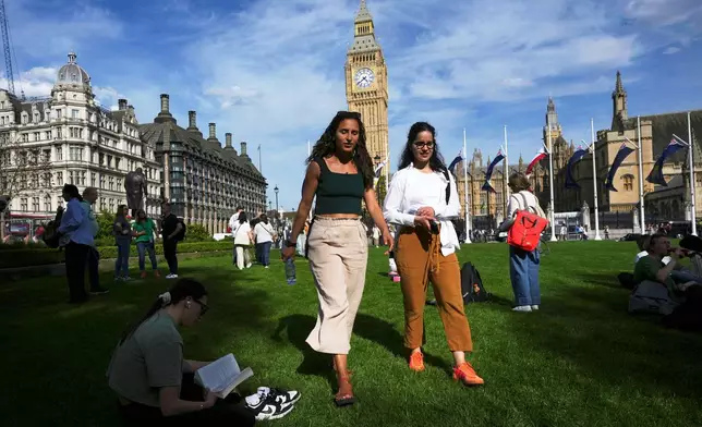 People walk in front of the House of Parliament on a sunny day in London, Thursday, May 1, 2025. (AP Photo/Kin Cheung)