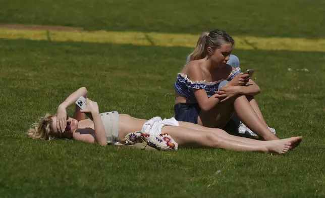 People sunbathe on a sunny day at a park in London, Wednesday, April 30, 2025. (AP Photo/Kin Cheung)