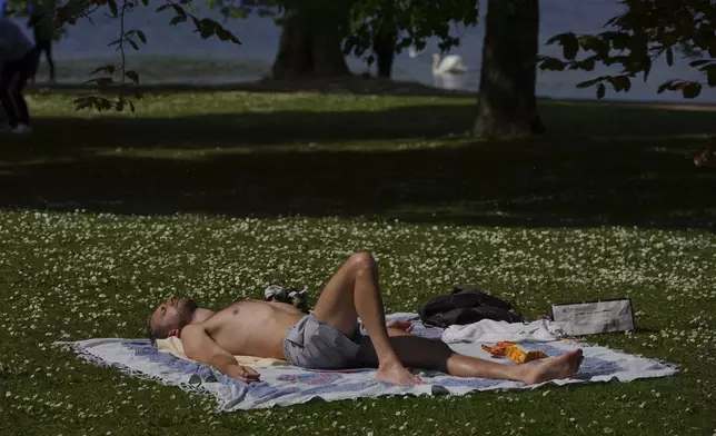 A man sunbathes on a sunny day at a park in London, Monday, April 28, 2025. (AP Photo/Kin Cheung)