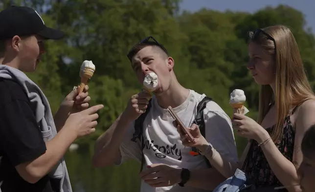 People have ice-cream on a sunny day at a park in London, Wednesday, April 30, 2025. (AP Photo/Kin Cheung)