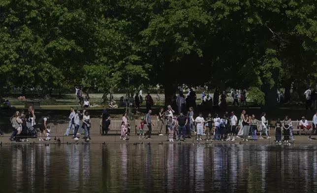 People walk on a sunny day at a park in London, Wednesday, April 30, 2025. (AP Photo/Kin Cheung)