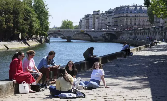 People enjoy the sun along the Seine river Wednesday, April 30, 2025 in Paris where temperatures rose up to 27 degrees Celsius (80 degrees Fahrenheit). (AP Photo/Michel Euler)