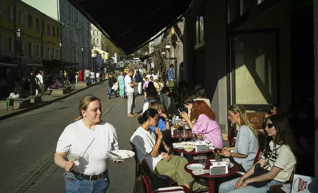 People sit at outdoor tables of a cafe on a sunny day as the temperature reached 25 degrees Celsius (77 degrees Fahrenheit) in Moscow, Russia, Saturday, April 19, 2025. (AP Photo/Pavel Bednyakov)