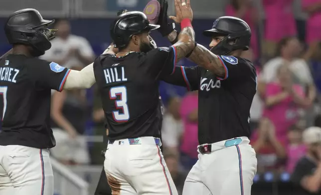 Miami Marlins' Agustín Ramírez, Derek Hill (3) and Jesús Sánchez (7) score on a double by Connor Norby during the fourth inning of a baseball game against the Tampa Bay Rays, Friday, May 16, 2025, in Miami. (AP Photo/Marta Lavandier)