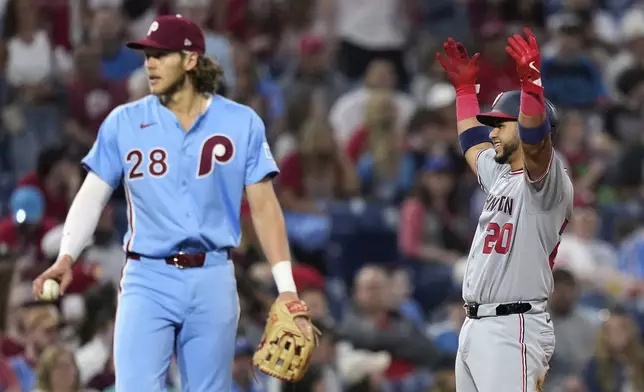 Washington Nationals' Keibert Ruiz, right, reacts past Philadelphia Phillies third baseman Alec Bohm after batting in a run on a fielding error by first baseman Bryce Harper during the sixth inning of a baseball game, Thursday, May 1, 2025, in Philadelphia. (AP Photo/Matt Slocum)