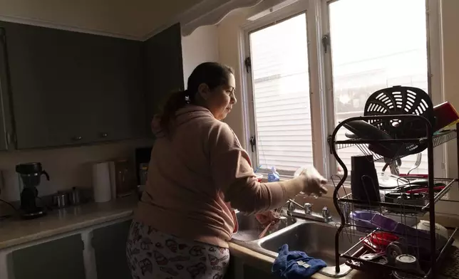 Arelis Ayala washes dishes while making breakfast for her family on Sunday, March 23, 2025, in Rochester, N.Y. (Toni Duncan via AP)