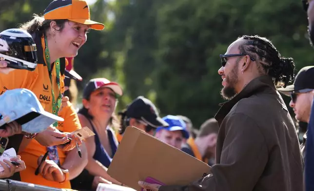 FILE - Ferrari driver Lewis Hamilton of Britain reacts with fans as he signs autographs as he arrives at the track ahead of the Australian Formula One Grand Prix at Albert Park, in Melbourne, Australia, Friday, March 14, 2025. (AP Photo/Asanka Brendon Ratnayake, File)