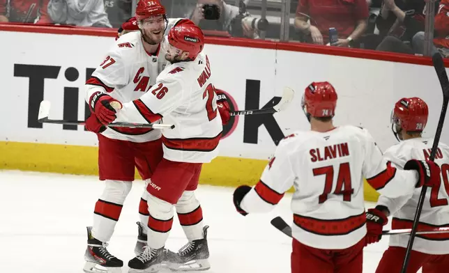 Carolina Hurricanes right wing Andrei Svechnikov (37) celebrates his goal with defenseman Sean Walker (26) and others in the third period of Game 5 of a second-round NHL hockey playoff series against the Washington Capitals Thursday, May 15, 2025, in Washington. (AP Photo/Nick Wass)