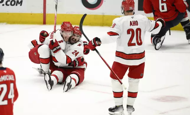 Carolina Hurricanes center Seth Jarvis (24) celebrates his empty net goal with right wing Andrei Svechnikov (37) and center Sebastian Aho (20) in the third period of Game 5 of a second-round NHL hockey playoff series against the Washington Capitals Thursday, May 15, 2025, in Washington. (AP Photo/Nick Wass)
