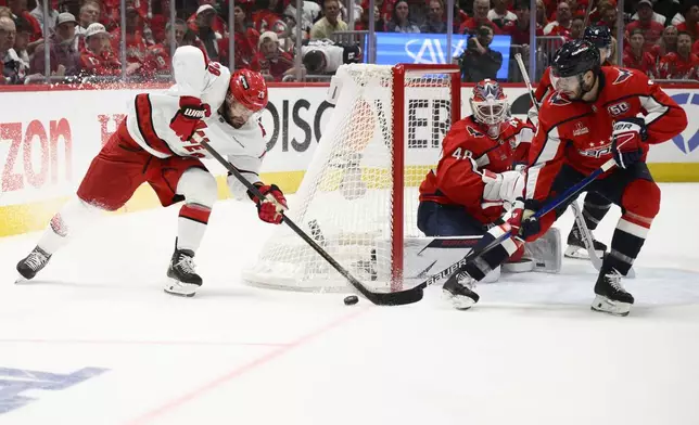Carolina Hurricanes left wing William Carrier (28) tries to get the puck past Washington Capitals goaltender Logan Thompson (48) and defenseman Matt Roy (3) in the second period of Game 5 of a second-round NHL hockey playoff series Thursday, May 15, 2025, in Washington. (AP Photo/Nick Wass)