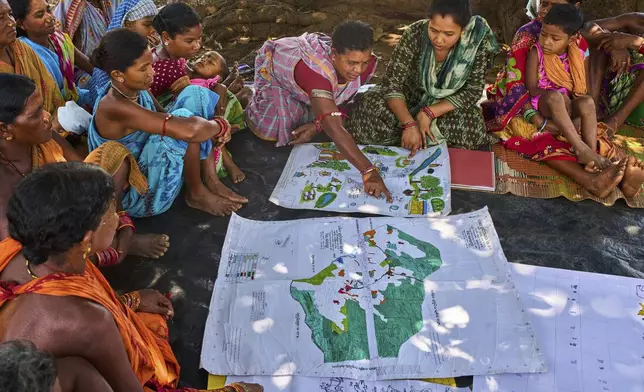 Kamala Kadria, third from right, a woman from the Gadaba Indigenous community, points to a spot on a map they made as others look on in Hatipakna village, Koraput district, in India's eastern state of Odisha, Wednesday, April 16, 2025. (AP Photo/Rafiq Maqbool)