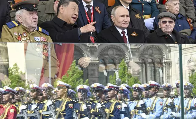 Russian President Vladimir Putin, centre right, and Chinese President Xi Jinpin, centre left, talk as Myanmar's servicemen are reflected in a stand's glass, during the Victory Day military parade in Moscow, Russia, Friday, May 9, 2025, during celebrations of the 80th anniversary of the Soviet Union's victory over Nazi Germany during the World War II. (Sergei Bobylev/Photo host agency RIA Novosti via AP)