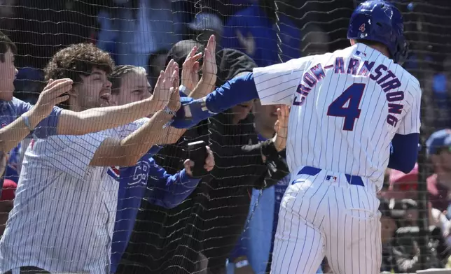 Chicago Cubs' Pete Crow-Armstrong, right, celebrates with fans after scoring on a sacrifice fly by Seiya Suzuki, of Japan, during the sixth inning of a baseball game against Chicago White Sox in Chicago, Sunday, May 18, 2025. (AP Photo/Nam Y. Huh)