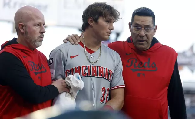 Cincinnati Reds outfielder Tyler Callihan (32) is helped off the field after colliding with the wall during the third inning of a baseball game against the Atlanta Braves, Monday, May 5, 2025, in Atlanta. (AP Photo/Butch Dill)