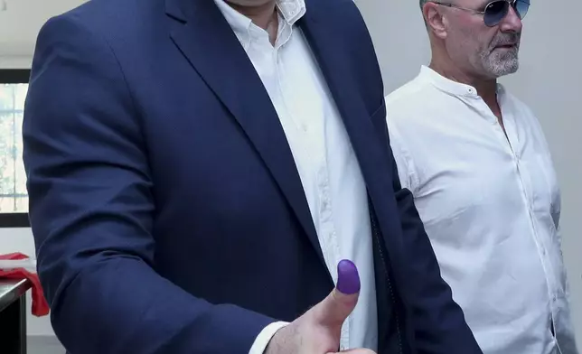 In this photo, released by the Lebanese Presidency press office, Lebanese president Joseph Aoun shows his ink-stained thumb after casting his vote at a polling station during municipal elections on his village of Aishiyeh, south Lebanon, Saturday, May 24, 2025. (Lebanese Presidency press office via AP)