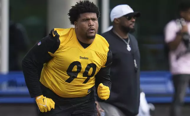 Pittsburgh Steelers head coach Mike Tomlin, right, watches as first round draft pick Derrick Harmon (99) warms up during the NFL football team's rookie camp in Pittsburgh, Friday, May 9, 2025. (AP Photo/Gene J. Puskar)