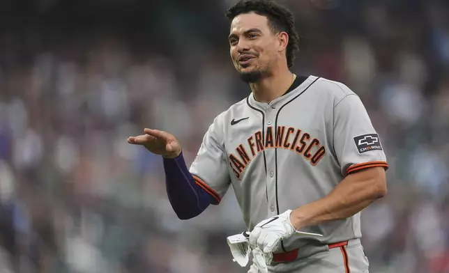 San Francisco Giants' Willy Adames jokes with players in the Colorado Rockies' dugout after he hit a single in the sixth inning of a baseball game, Thursday, June 12, 2025, in Denver. (AP Photo/David Zalubowski)
