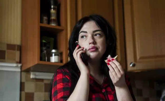 Olha Kurtmalaieva speaks via a phone while having a breakfast at her apartment in Kyiv, Ukraine, on Tuesday, June 17, 2025. (AP Photo/Evgeniy Maloletka)