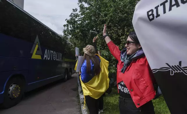 Olha Kurtmalaieva waves to Ukrainian marine soldiers sitting in a bus after a POWs exchange between Russia and Ukraine, in Chernyhiv region, Ukraine, Saturday, June 14, 2025. (AP Photo/Evgeniy Maloletka)
