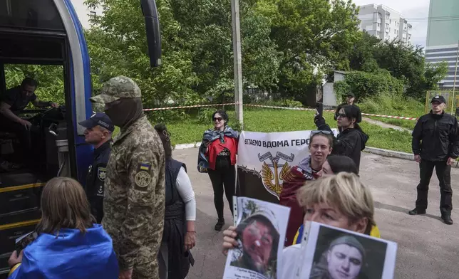 Olha Kurtmalaieva holds a placard for Ukrainian marine soldiers coming out from a bus after a POWs exchange between Russia and Ukraine, in Chernyhiv region, Ukraine, Saturday, June 14, 2025. (AP Photo/Evgeniy Maloletka)