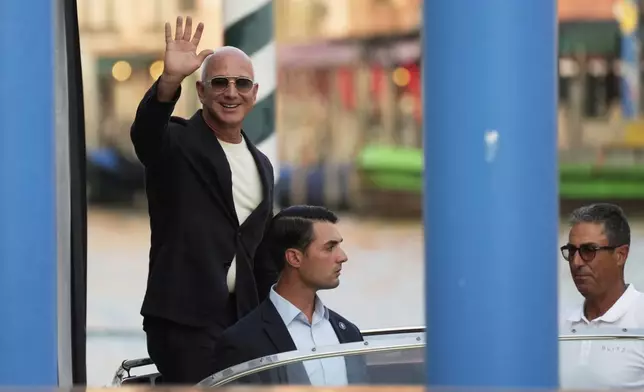 Amazon multi-billionaire founder Jeff Bezos waves as he leaves by boat a hotel in Venice, Italy, on Wednesday, June 25, 2025, ahead of festivities in the lagoon city reportedly linked to his wedding with Lauren Sanchez. (AP Photo/Luca Bruno)