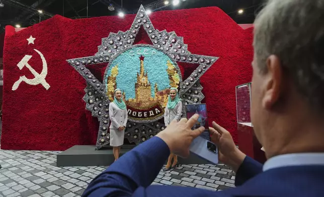 Participants pose for a photo in front of a model of the Order of Victory on the sidelines of the St. Petersburg International Economic Forum in St. Petersburg, Russia, Wednesday, June 18, 2025. (AP Photo/Dmitri Lovetsky)