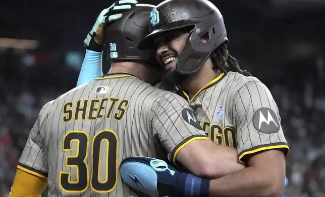 San Diego Padres' Fernando Tatis Jr., right, celebrates with Gavin Sheets (30) after scoring against the Arizona Diamondbacks on a double hit by Luis Arraez in the fifth inning during a baseball game, Sunday, June 15, 2025, in Phoenix. (AP Photo/Rick Scuteri)