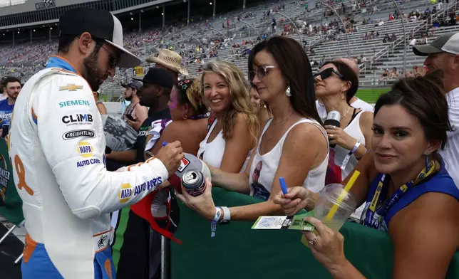 Driver Chase Elliott signs autographs for fans before a NASCAR Cup Series auto race, Saturday, June 28, 2025, in Hampton, Ga. (AP Photo/Butch Dill)