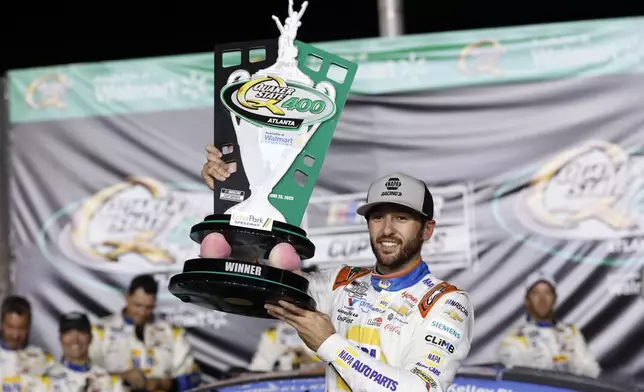 Driver Chase Elliott (9) celebrates with the trophy in Victory Lane after winning a NASCAR Cup Series auto race, Saturday, June 28, 2025, in Hampton, Ga. (AP Photo/Butch Dill)