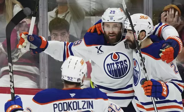 Edmonton Oilers' Leon Draisaitl (29) celebrates after his winning goal against the Florida Panthers with Evan Bouchard (2) during the first overtime period in Game 4 of the NHL hockey Stanley Cup Final in Sunrise, Fla., Thursday, June 12, 2025. (Nathan Denette/The Canadian Press via AP)