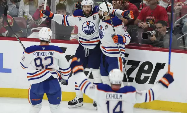 Edmonton Oilers' Leon Draisaitl (29) celebrates after his winning goal against the Florida Panthers with Evan Bouchard (2), Vasily Podkolzin (92) and Mattias Ekholm (14) during the first overtime period in Game 4 of the NHL hockey Stanley Cup Final in Sunrise, Fla., Thursday, June 12, 2025. (Nathan Denette/The Canadian Press via AP)