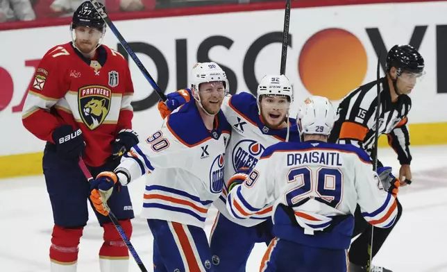 Edmonton Oilers' Vasily Podkolzin (92) celebrates after his goal with Corey Perry (90) and Leon Draisaitl (29) as Florida Panthers' Niko Mikkola (77) looks on during the second period in Game 4 of the NHL hockey Stanley Cup Final in Sunrise, Fla., Thursday, June 12, 2025. (Nathan Denette/The Canadian Press via AP)
